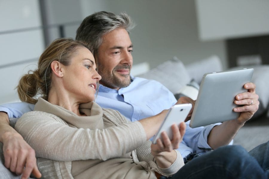 A couple looking at a tablet screen on the sofa.