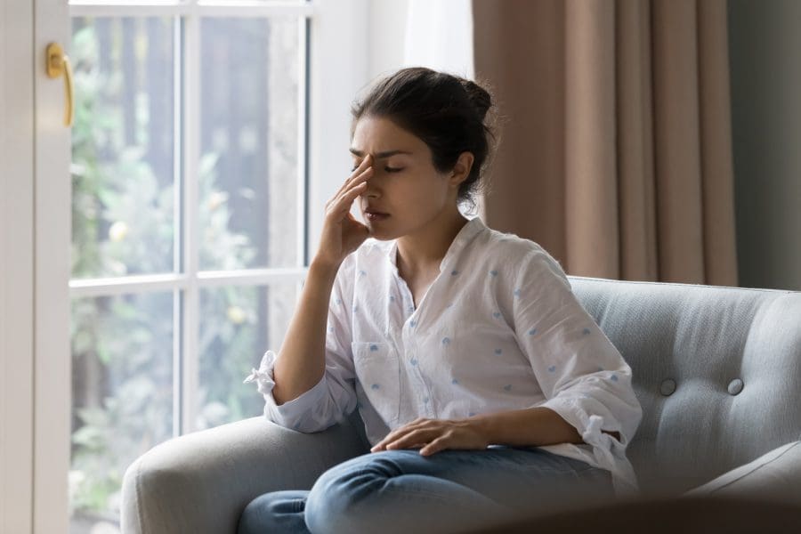 A young woman looking stressed at home.