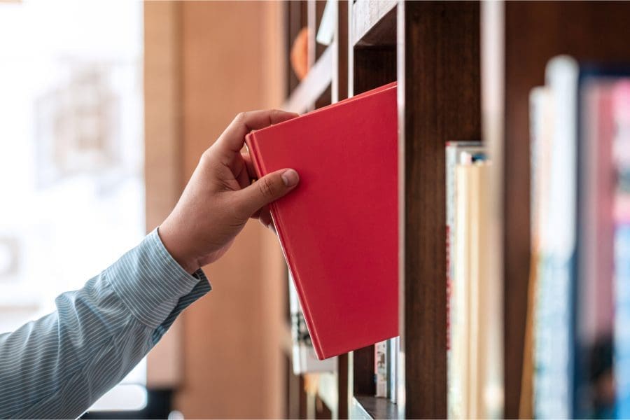 Someone picking up a book in a library.