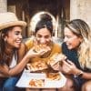 Three women eating pizza in an exotic location