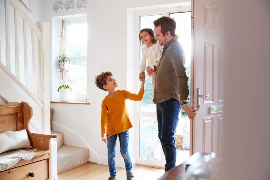 A father and two children walking into their home.