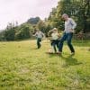 Multi-generational family playing football in a park.