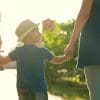 A family with a young child holding hands outdoors.