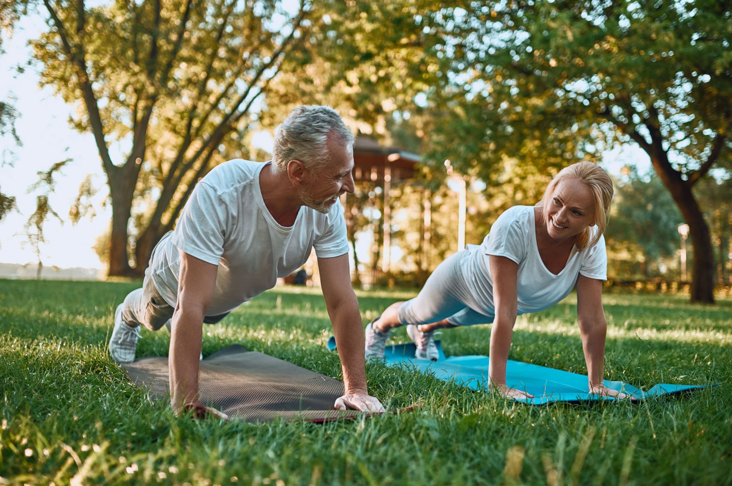 A couple doing yoga in a park.