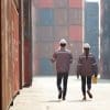 Two workers walking between shopping containers.