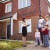 A family standing outside a house with a real estate agent.