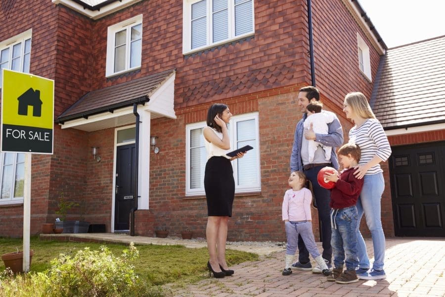 A family standing outside a house with a real estate agent.