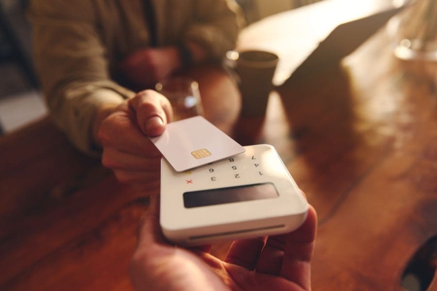 A person using their debit card to pay in a café.