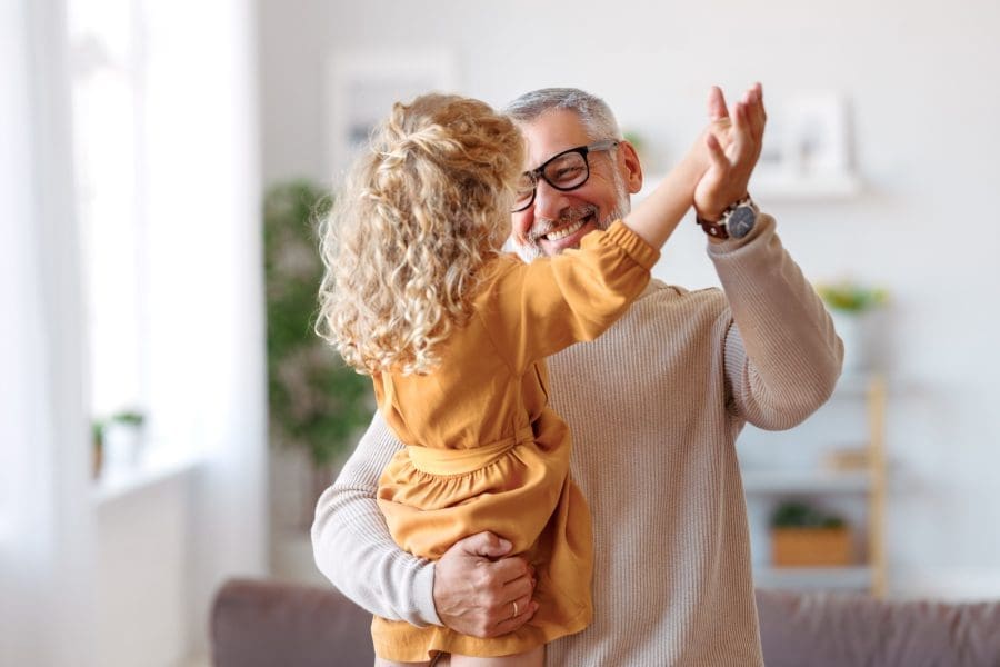 A grandfather playing with his granddaughter at home.