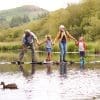 A family walking across stepping stones in a park.